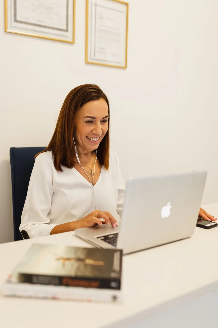 Blácia Gonzales sorrindo diante do notebook, em seu consultório